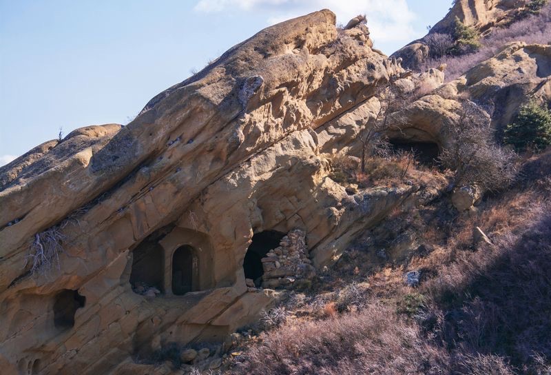 Rock-cut monastery cells carved into the sandstone slope